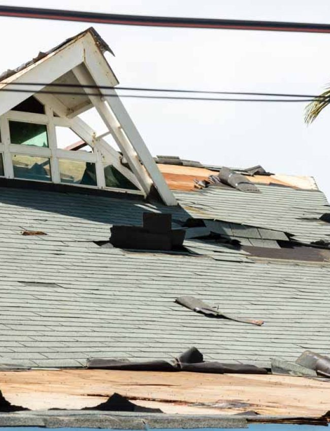 A badly damaged building post-typhoon, with several shingles removed and parts of the roof destroyed