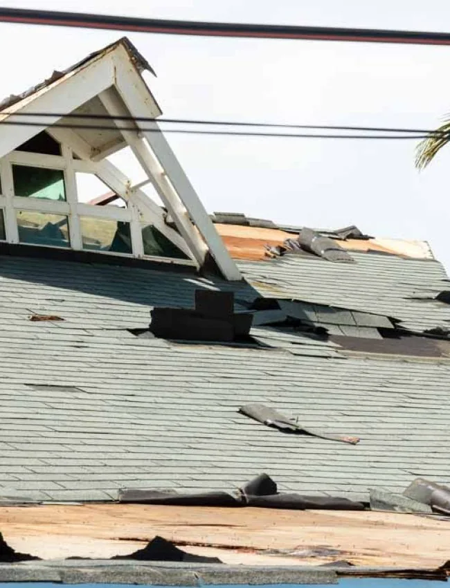A badly damaged building post-typhoon, with several shingles removed and parts of the roof destroyed