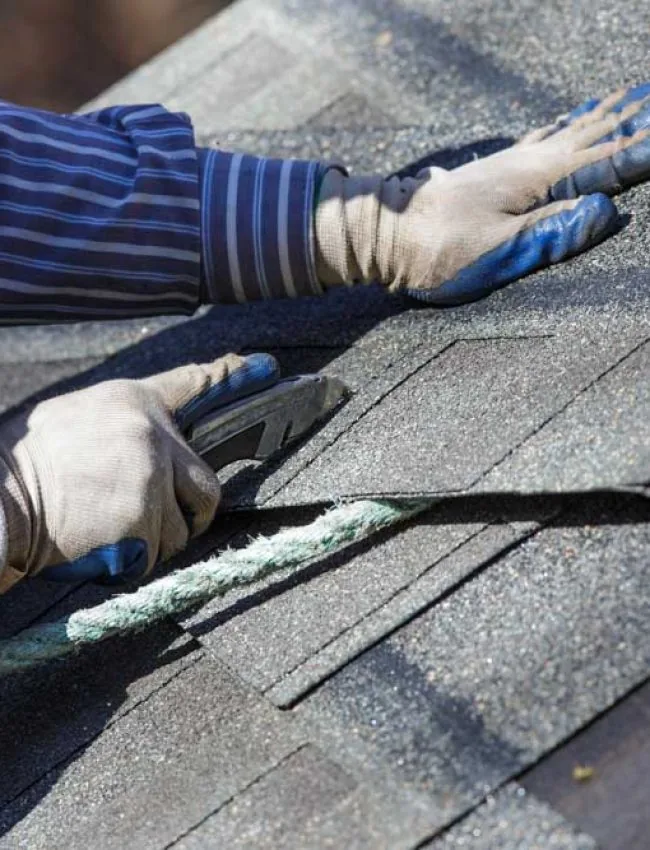 A skilled roofer cutting shingles to fit properly on the area of repair or replacement