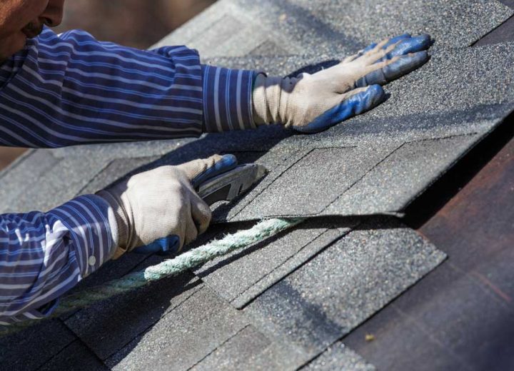 A skilled roofer cutting shingles to fit properly on the area of repair or replacement