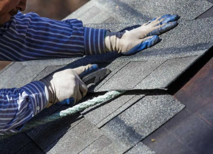 A skilled roofer cutting shingles to fit properly on the area of repair or replacement