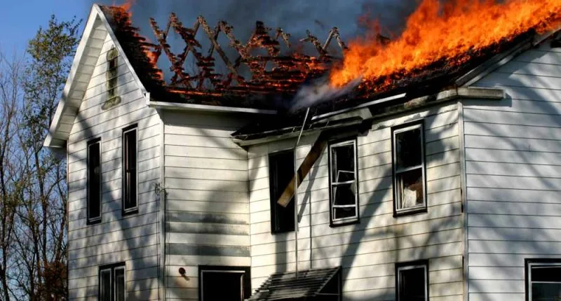 Second story fire in a white house with roof up in flames