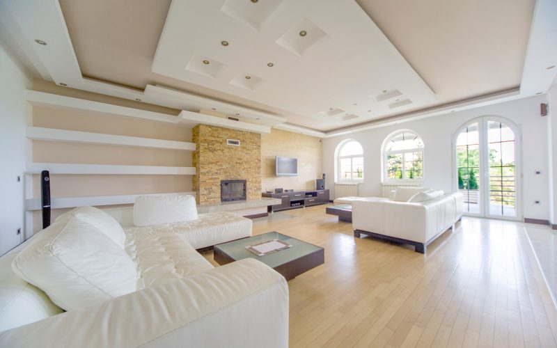Interior of a luxurious house with wide living room and long couches.