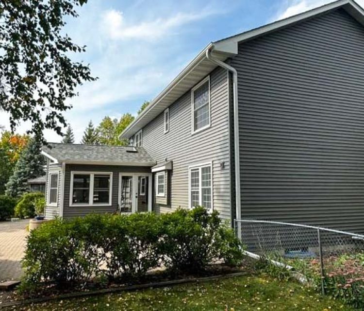 Vinyl Siding of a two-story of a house with concrete backyard patio
