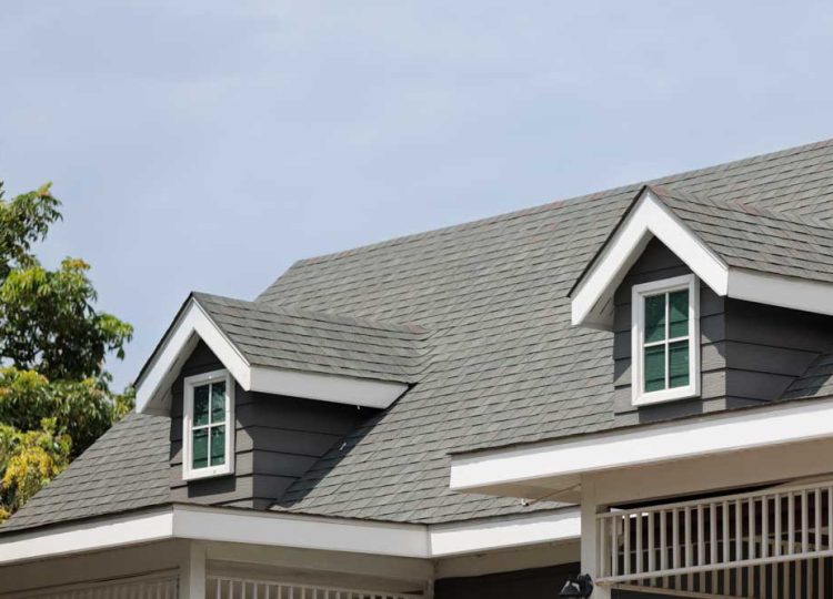 Roof shingles with garret on top of the house. with two dormer roofs, dark asphalt tiles on the roof