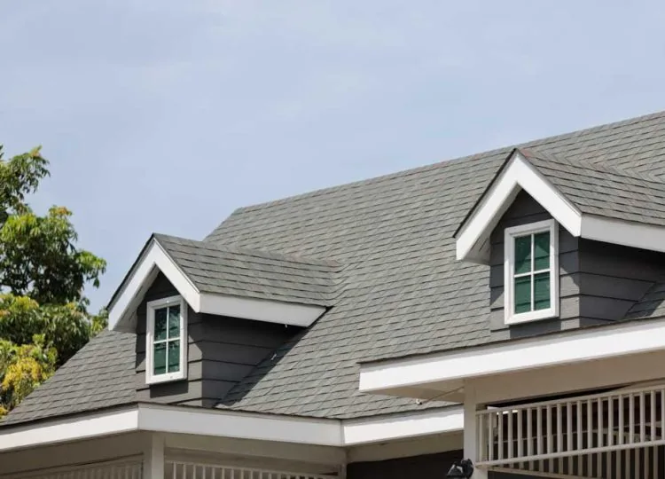 Roof shingles with garret on top of the house. with two dormer roofs, dark asphalt tiles on the roof
