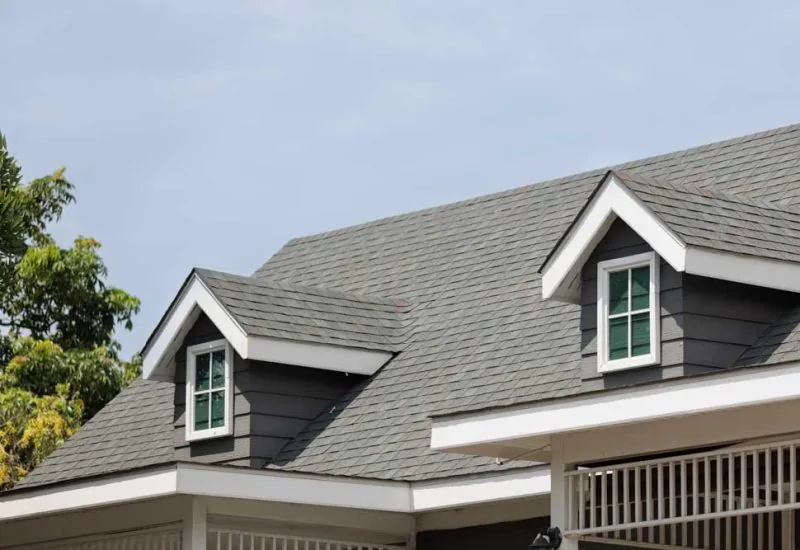 Roof shingles with garret on top of the house. with two dormer roofs, dark asphalt tiles on the roof