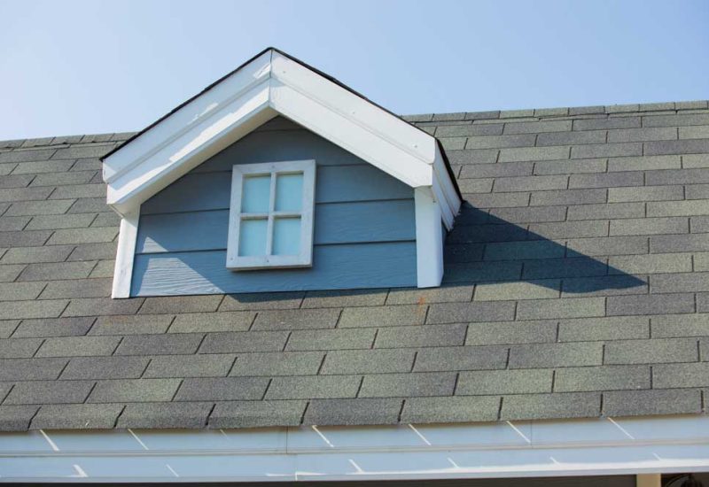 A dormer roof on a sloped part of the main roof with asphalt shingles