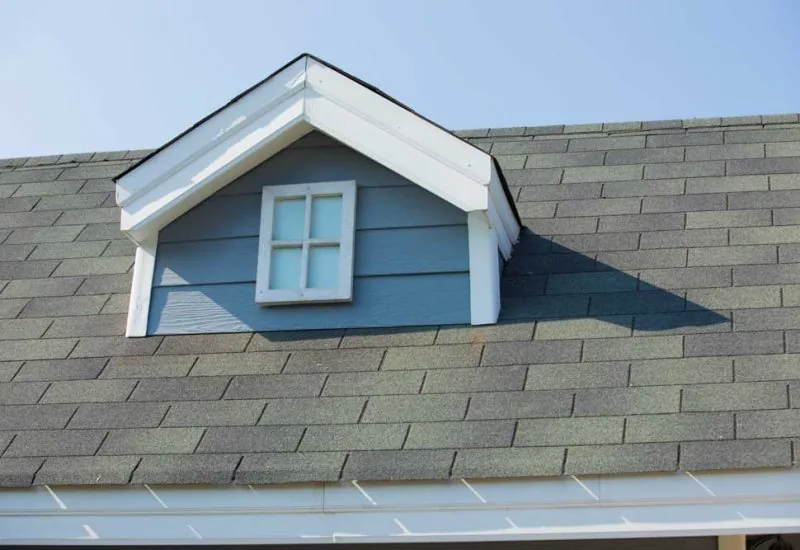 A dormer roof on a sloped part of the main roof with asphalt shingles