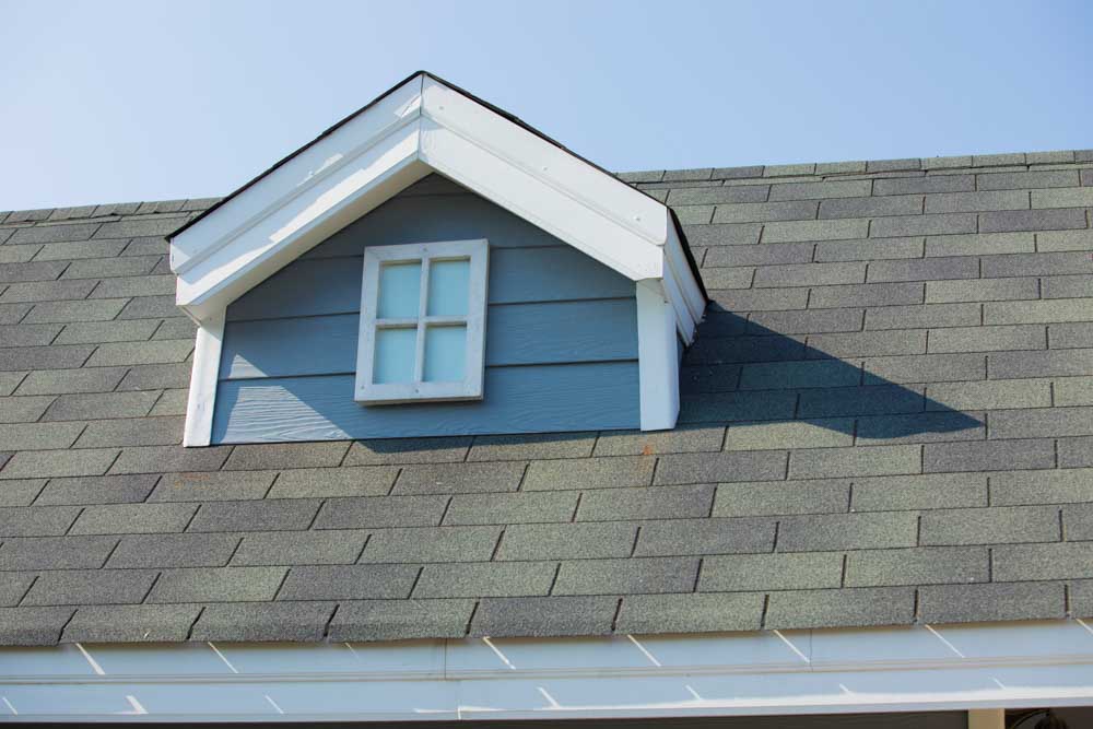 A dormer roof on a sloped part of the main roof with asphalt shingles