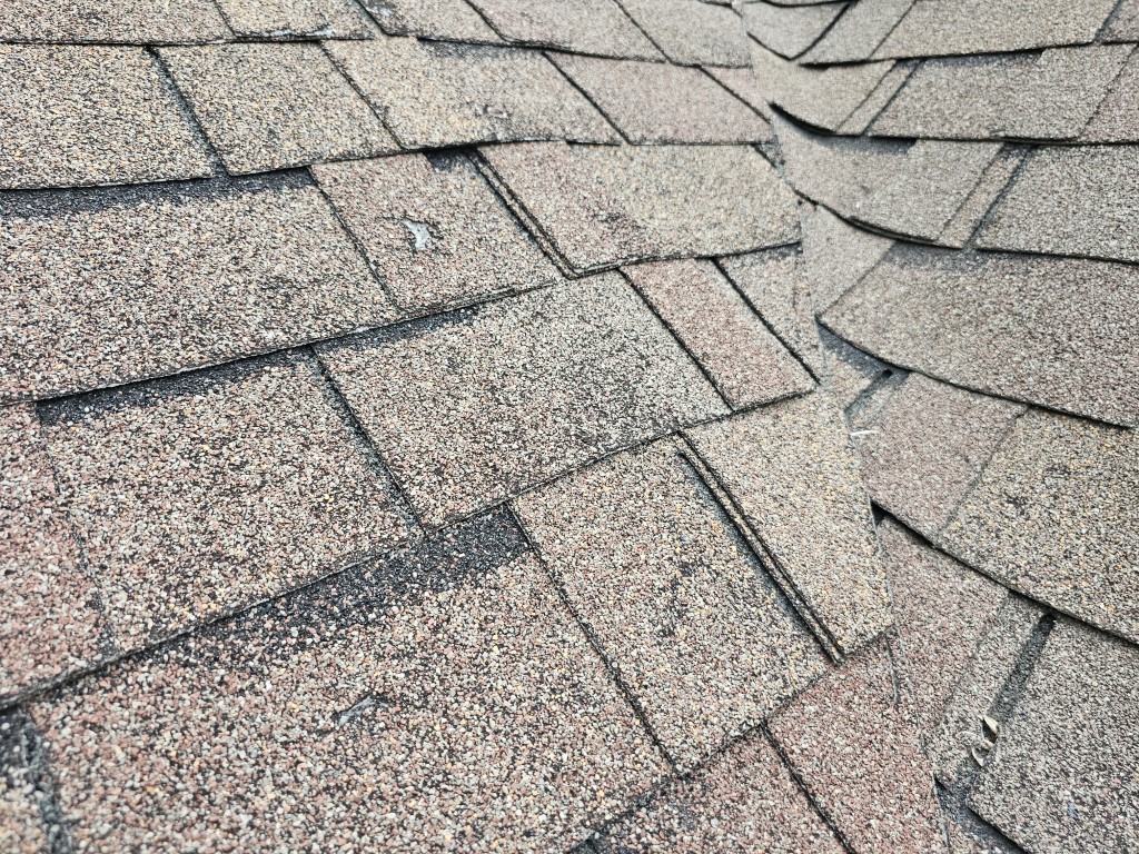 Hail-damaged roof in Prior Lake, MN before replacement by BN Exteriors showing impact damage on shingles