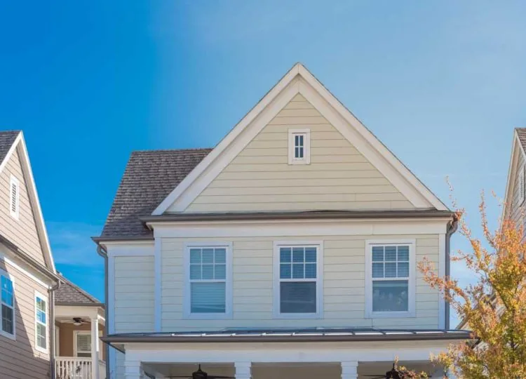 Upscale cottage style homes in suburbs Dallas, Texas with wood siding, covered porch patio with ceiling fans. Colorful autumn leaves and white cladding layer thermal insulation, weather resistance