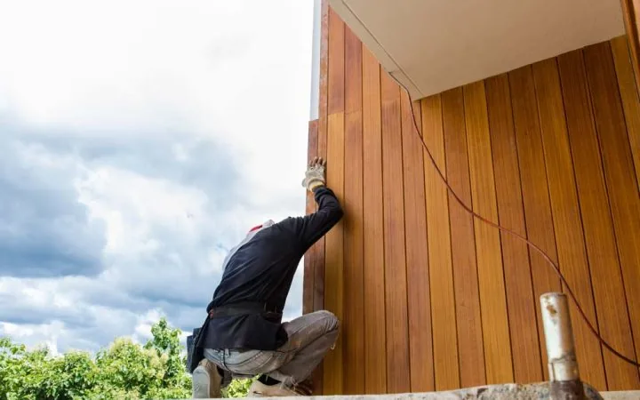 A skilled worker installing siding using Fiber Cement Board on the exterior wall of a property