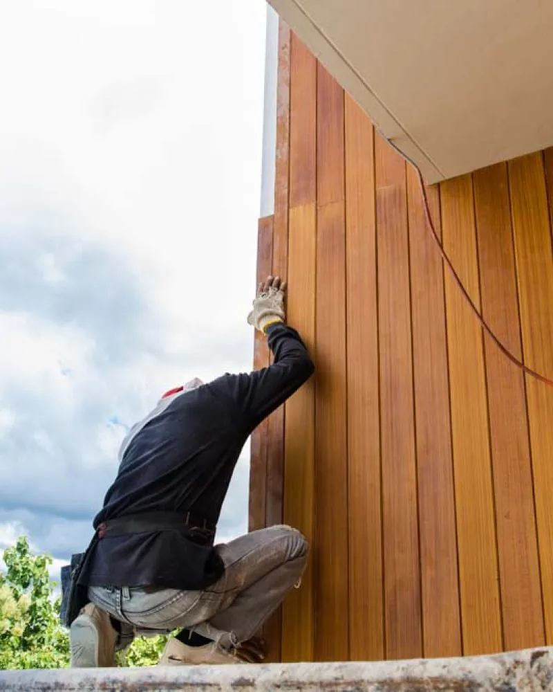 A skilled worker installing siding using Fiber Cement Board on the exterior wall of a property
